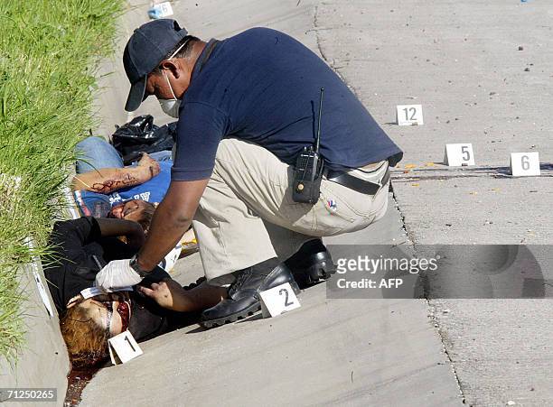 Quezaltepeque, EL SALVADOR: Un forense de la Policia Nacional Civil examina el cadaver de dos mujeres, miembros de la pandilla "mara 18", el martes...