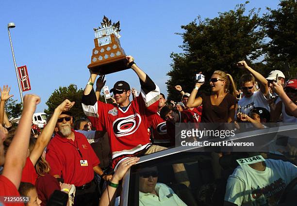 Goalkeeper Cam Ward of the Carolina Hurricanes holds the Conn Smythe trophy aloft during a parade to celebrate the team's game seven Stanley Cup...