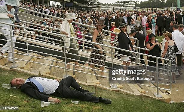 Man lies on the ground as race-goers walk past him on the first day of Royal Ascot, at the Ascot Racecourse on June 20, 2006 in Ascot, England. The...