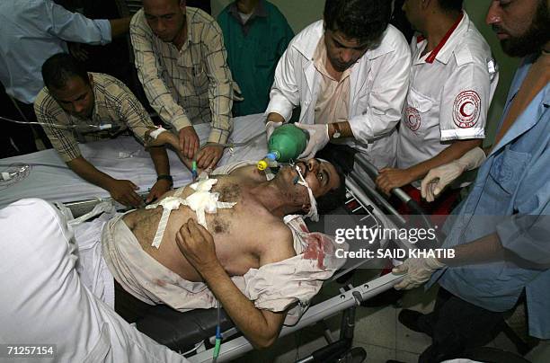 Medics rush with Palestinian Zakaria al-Barbaraoui in the Naser hospital in the southern Gaza Strip town of Khan Yunis 21 June 2006, following an...