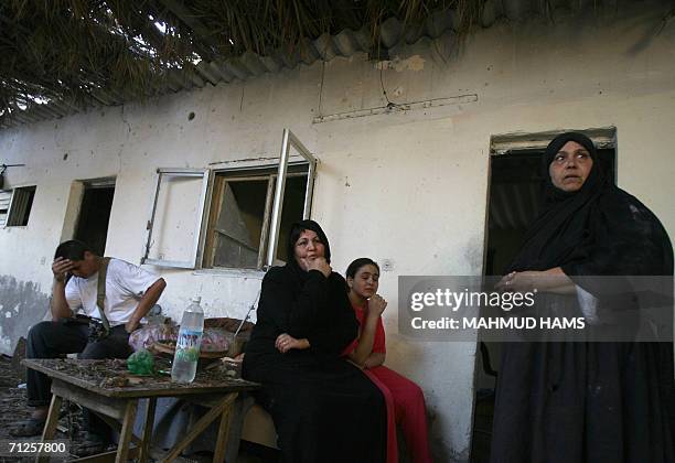 Palestinian family members sit close to where a woman was killed in her home hit during an Israeli missile strike in Khan Yunis in the southern Gaza...