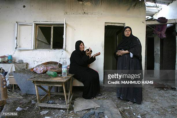 Palestinian women sit in the grounds of a damaged residence close to where a woman was killed after the house was hit during an Israeli missile...