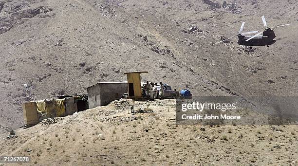 An American troop transport helicopter passes an Afghan outpost after delivering soldiers to a U.S. Base near the village of Deh Afghan on June 22,...