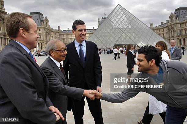 Chinese architect of the Louvre Pyramid Ieoh Ming Pei shakes hands with a tourist next to the French director of the Louvre museum Henri Loyrette and...