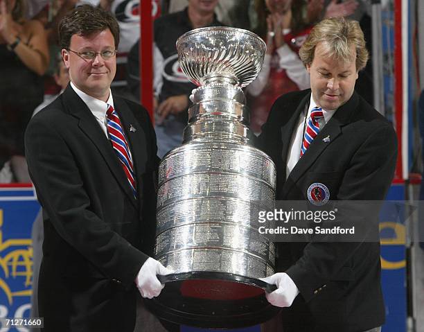 Curators from the Hockey Hall of Fame, Craig Campbell and Phil Pritchard carry the Stanley Cup onto the ice after the Carolina Hurricanes defeated...