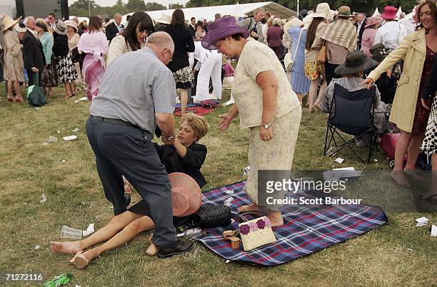 Woman is helped to her feet as race-goers make their way home after Ladies' Day, the third day of Royal Ascot, at the Ascot Racecourse on June 22,...
