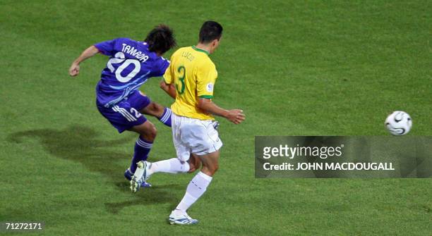 Japanese forward Keiji Tamada shoots and scores in despite of Brazilian defender Lucio's opposition during the opening round Group F World Cup...