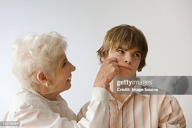 woman grabbing grandson's cheek - つねる ストックフォトと画像