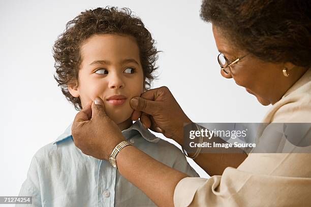 grandmother pinching grandson's cheeks - pressure photos et images de collection