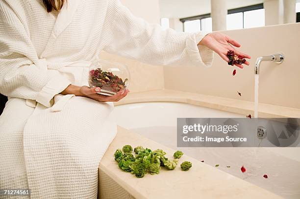 woman dropping rose petals into bath - essence day stock pictures, royalty-free photos & images