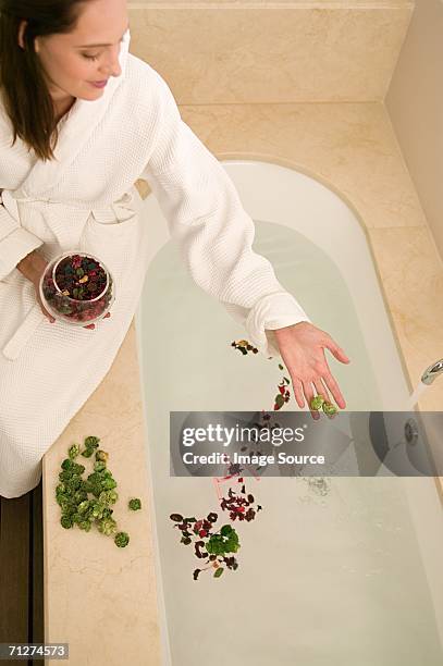 woman dropping rose petals into bath - taking a bath stock pictures, royalty-free photos & images