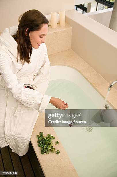 woman dropping rose petals in bath - essence day stock pictures, royalty-free photos & images