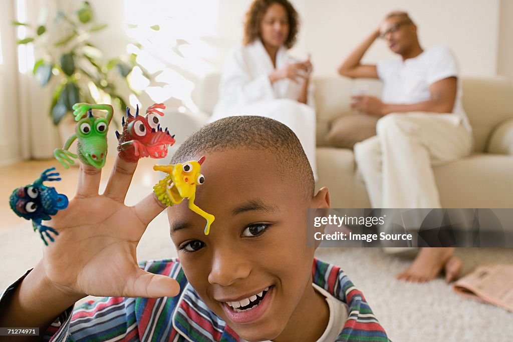 Boy in living room playing with monster finger puppets