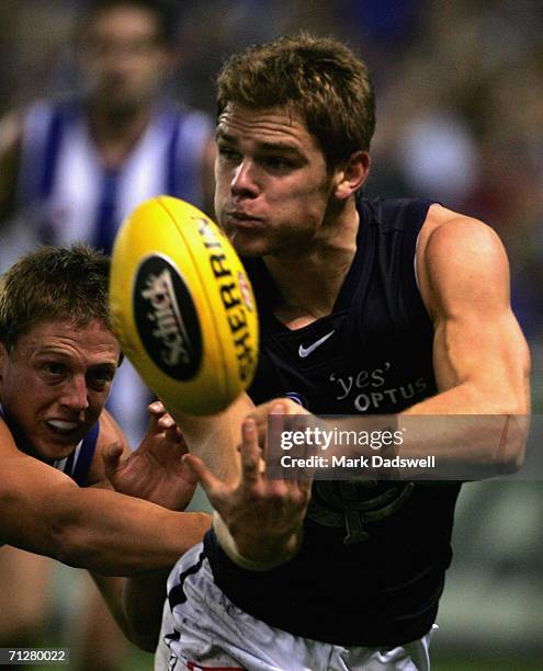 Adam Bentick of the Blues handballs clear of Daniel Harris of the Kangaroos during the round 12 AFL match between the Kangaroos and Carlton at the...