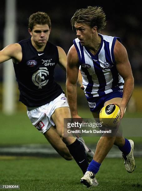 Jess Sinclair of the Kangaroos breaks away from Adam Bentick of the Blues during the round 12 AFL match between the Kangaroos and Carlton at the...