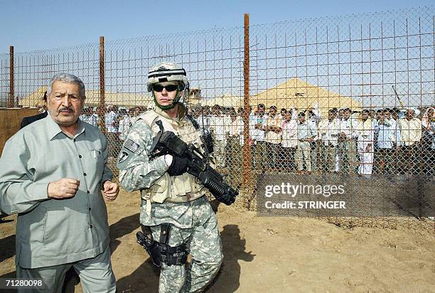 Solder escorts Iraqi former deputy prime minister Abd Mutlaq al-Jebouri as he attends the release of prisoners 23 June 2006 at Abu Ghraib prison west...