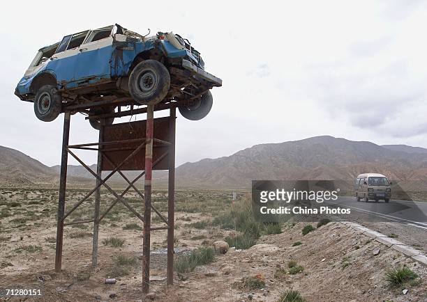 The wreckage of a car is installed on a billboard to warn drivers to drive carefully at the Qinghai-Tibet Highway on June 19, 2006 in Golmud of...