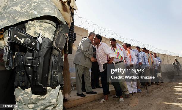 Iraqi freed prisoners line up to shake hands with Iraqi former Deputy Prime Minister Abd Mutlaqi al-Jabouri as U.S soldiers stand guard on June 23,...