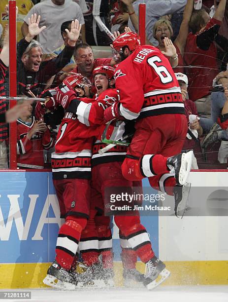 Justin Williams of the Carolina Hurricanes is mobbed by teammates Eric Staal and Bret Hedican after Williams scored an empty net goal against the...