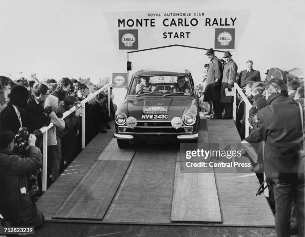 Spectators watch as Roger Clark and navigator Brian Melia drive the Ford Cortina MkI off the ramp for the start of the Monte Carlo Rally from the...