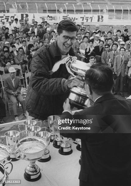 Peter Warr of Great Britain and driver of the Lotus 23B Ford celebrates with the trophies after winning the first Japanese Grand Prix for sports cars...