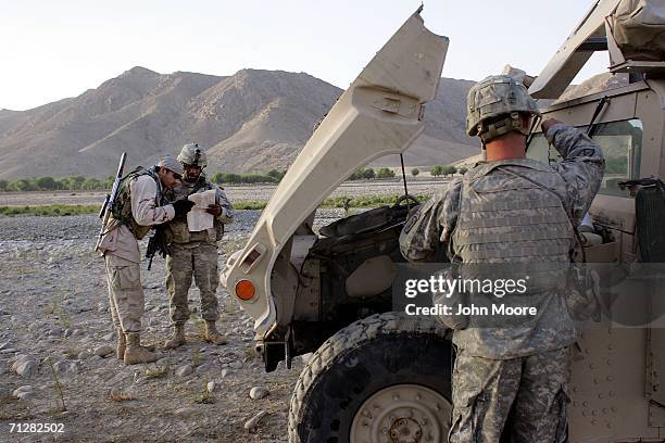 Army Sfc. Lydell Lacy and an Afghan interpreter read a map next to their broken down humvee June 23, 2006 near Deh Afghan in the Zabul province of...