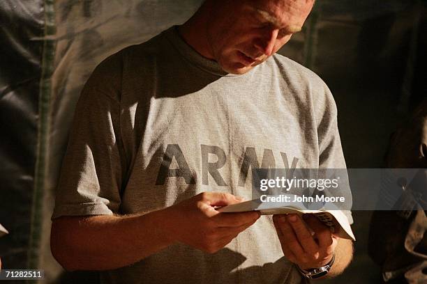 Army Sgt. Billy Abbott from Addison, Alabama reads from scripture during a prayer service for American soldiers at a U.S. Base June 23, 2006 near Deh...