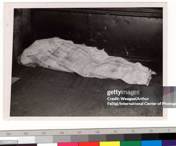 Dead body lies on the street hidden under a blanket, New York, New York, circa 1942.