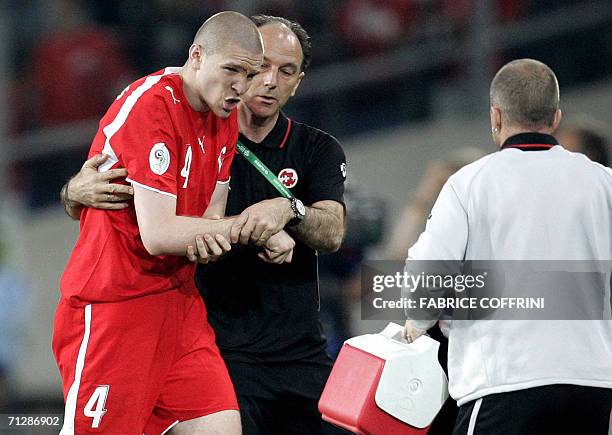 Swiss defender Philippe Senderos is assisted by a trainer as he leaves the field after dislocating his shoulder during the World Cup 2006 group G...