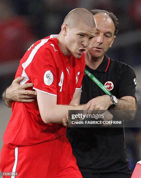 Swiss central defender Philippe Senderos leaves the pitch helped by a member of his team's medical staff after after dislocating his shoulder during...