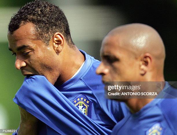 Bergisch Gladbach, GERMANY: Brazil's team captain Cafu wipes his face as he runs with teammate Roberto Carlos, 24 June 2006, during a training...