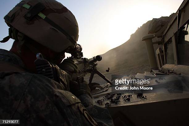 An American soldier from the 2nd Battalion, 4th Infantry Regiment fires a machine gun from a U.S. Base while participating in Operation Mountain...