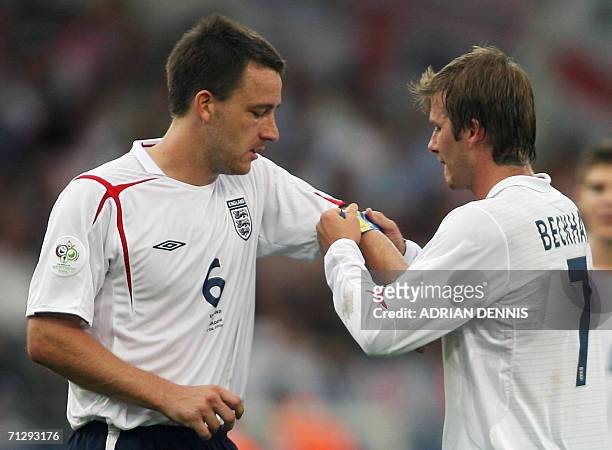 English midfielder David Beckham places the captain's armband on English defender John Terry as he leaves the game during the round of 16 World Cup...