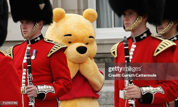 Winnie the pooh stands behind the guards on the Forecourt of Buckingham Palace for the Queen's 80th Birthday - Children's Garden Party on June 25,...