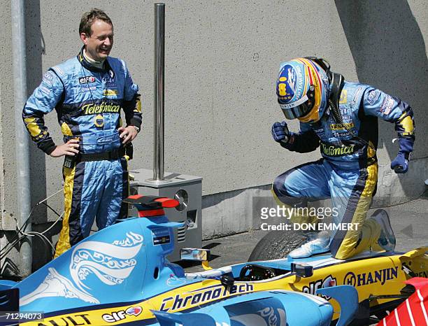 Fernando Alonso of Spain racing for the Renault F1 racing team kneels on his car in victory lane as team manager Steve Nielsen watches 25 June 2006...