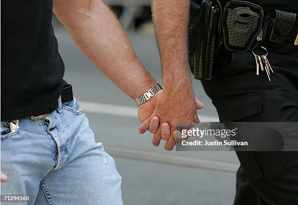 Two men hold hands as they participate in the 36th annual LGBT Pride Parade June 25, 2006 in San Francisco. Hundreds of thousands of spectators lined...