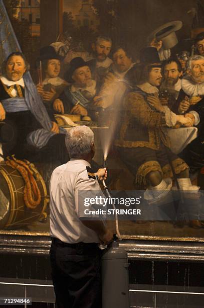 Amsterdam, NETHERLANDS: A museum guard attempts to wash off chemicals sprayed by a 69-year-old unidentified man who attacked the painting,...