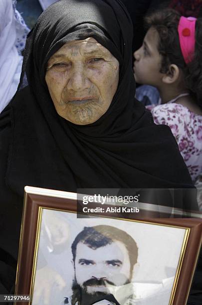 Palestinian woman holds a photo of her son, jailed in an Israeli prison, during a demonstration at the headquarters of the Red Cross June 26, 2006 in...