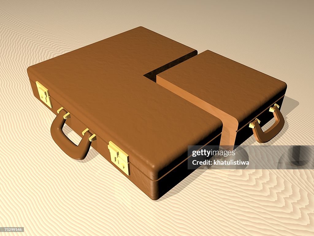 Close-up of two briefcases on sand