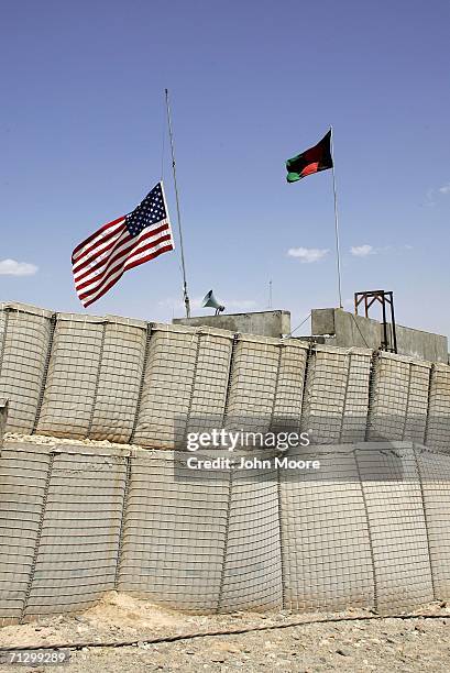 An American flag flying at half staff stands next to an Afghan flag at a U.S. Special Forces compound at an American base June 26, 2006 at Deh Afghan...