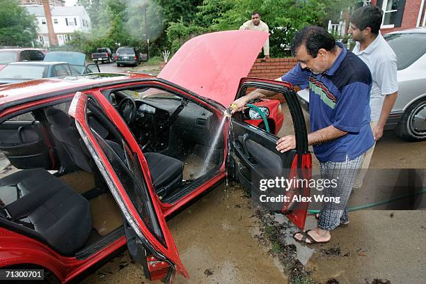 Local resident Tariq Baig washes away the mud in his car which was caused by a flooding throughout the night June 26, 2006 in the Huntington area of...