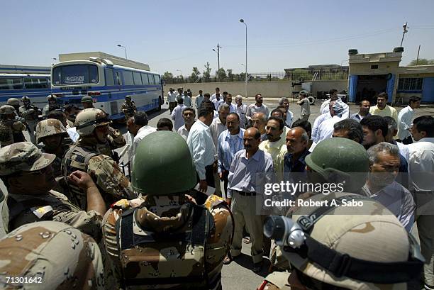 Some of more than 100 detainees released from Abu Ghraib Prison meet with Iraqi Army officials in a city bus depot before leaving reunited with their...