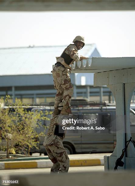 Iraqi soldiers climb on top of a bus depot shelter to provide security for released prisoners and their families June 11, 2006 in Baghdad, Iraq. More...