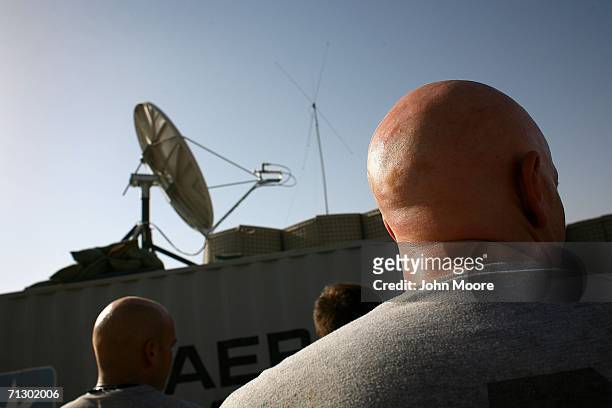 Satellite dish provides soldiers with free broadband internet as others do morning exercise at a U.S. Base at Deh Afghan June 27, 2006 in the Zabul...