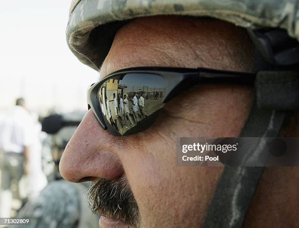 Soldier looks on as detainees stand in the Abu Ghraib prison yard while waiting to be released on June 27, 2006 in Baghdad, Iraq. Another 500...