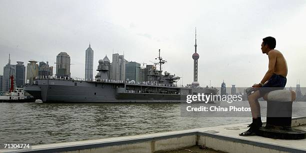 Migrant worker looks at the flagship of the U.S. Navy's Pacific fleet USS Blue Ridge which docked at port on June 27, 2006 in Shanghai, China. The...