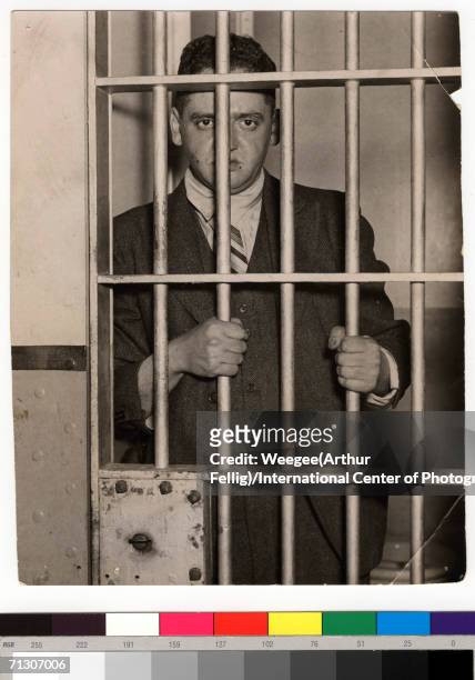 'Behind Bars...for Being a Dope...' by Weegee, circa 1937. The American photographer Weegee looks out from a jail cell.