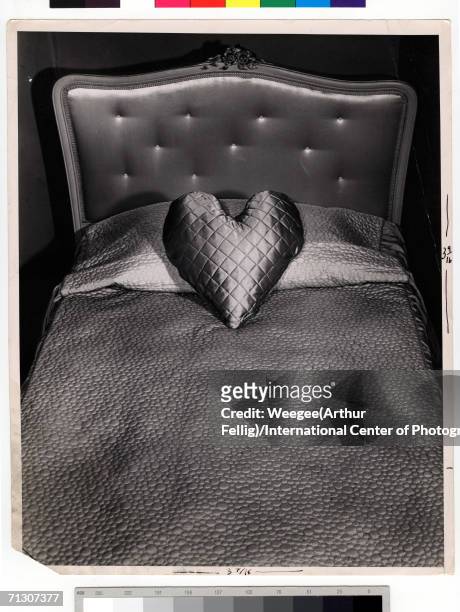 Photograph by Weegee of an heart-shaped pillow on a twin bed, circa 1945.