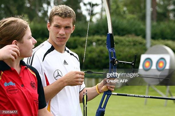 German forward Lukas Podolski listens to the advices of an unidentified archery trainer as he prepares an arrow 28 June 2006 as the German national...