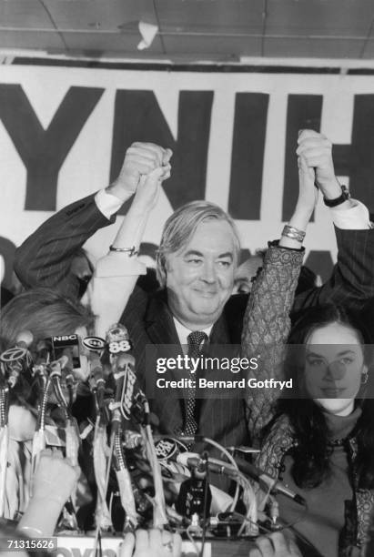 American sociologist, diplomat, and senator Daniel Patrick Moynihan rasies his arms in victory and holds the hand of his daughter, actress, musician,...